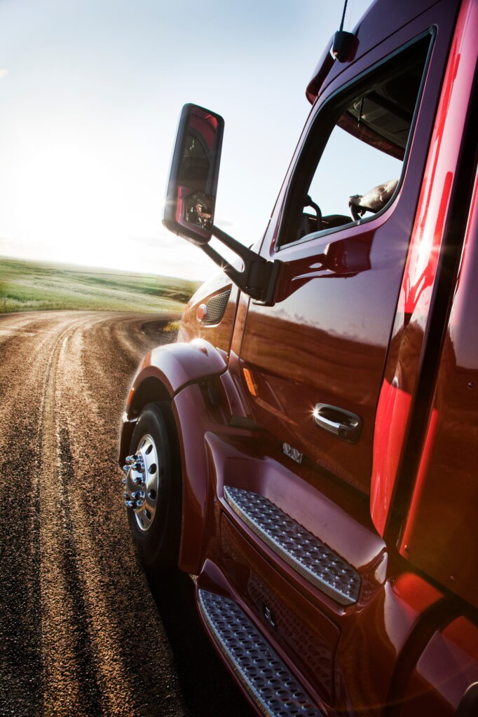 Close up side view looking forward of a commercial truck on a highway at sunset.